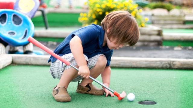a boy plays mini golf