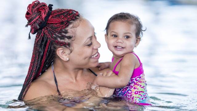 a mom and baby swim at an indoor swimming pool