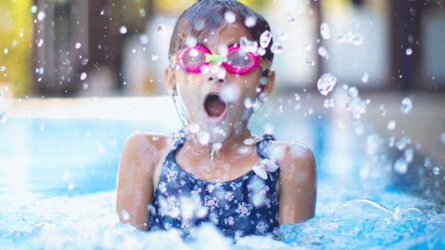 A girl swimming in a pool with pink goggles