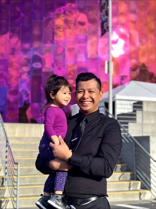 a dad and daughter pose in front of seattle wall murals at Seattle Center