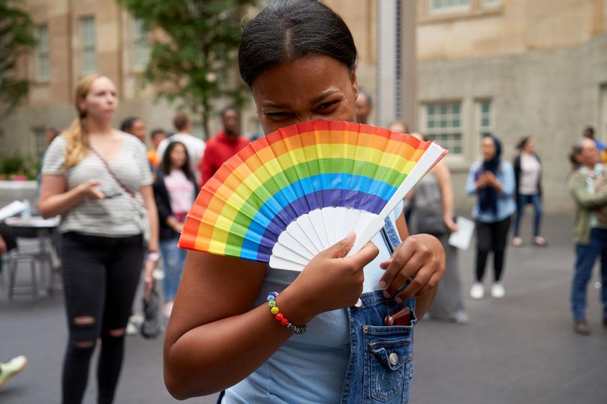 Black woman holding a rainbow fan and wearing a rainbow bracelet at the Smithsonian's annual Pride Event 