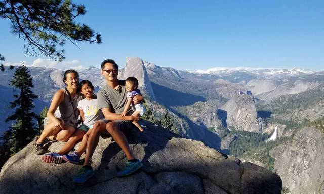 A family sits on a scenic rock in Yosemite