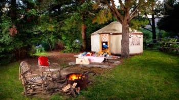 chairs and a firepit sit outside this yurt camping spot