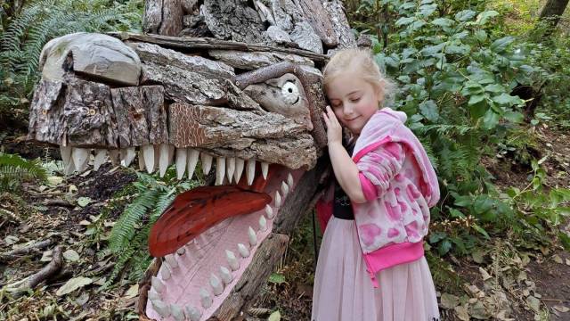 a girl hugs a dragon art piece price sculpture forest outdoor activities seattle