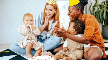 a picture of two moms and two babies clapping, a cute first birthday party idea
