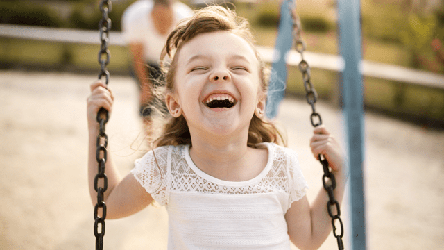 little girl laughing on a swing