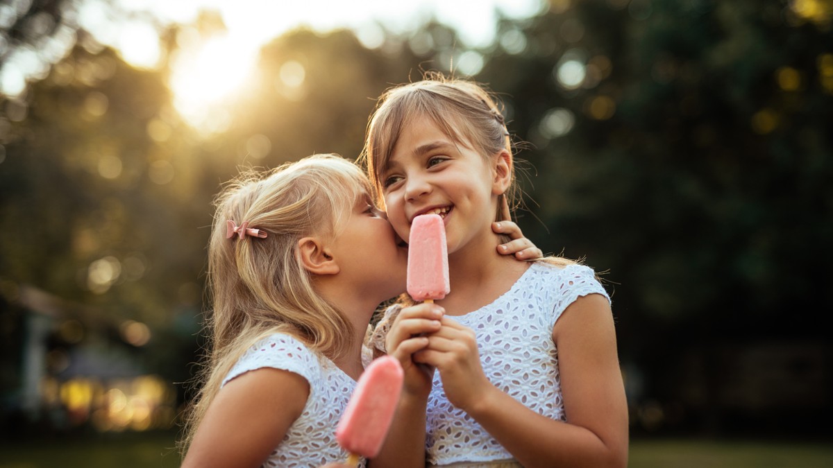 two girls eating popsicles on a summer evening