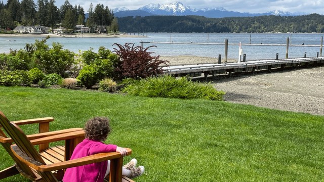 a little girl sits in a chair looking out at mountains above hood canal during a weekend trips from seattle