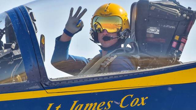 a blue angel show pilot waves from the cockpit