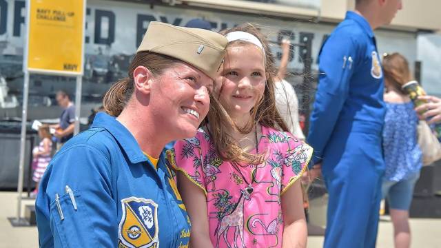 a female blue angel show pilot stands next to a young girl 