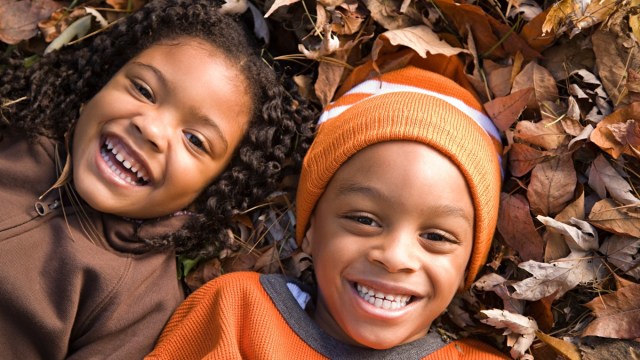 two smiling kids lay in the fallen leaves during fall free things to do