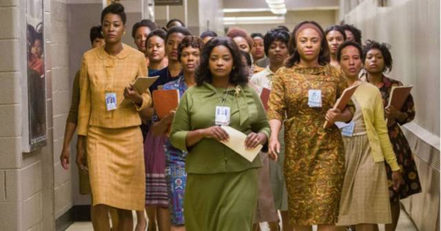 A group of black women wearing badges walk down a hall
