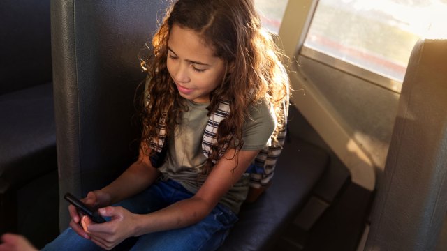 middle school girl texting on a bus