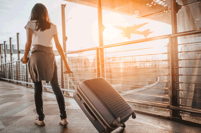 teen pulling suitcase at airport on family vacation