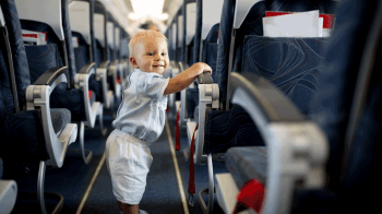 toddler walking through aisle of an airplane