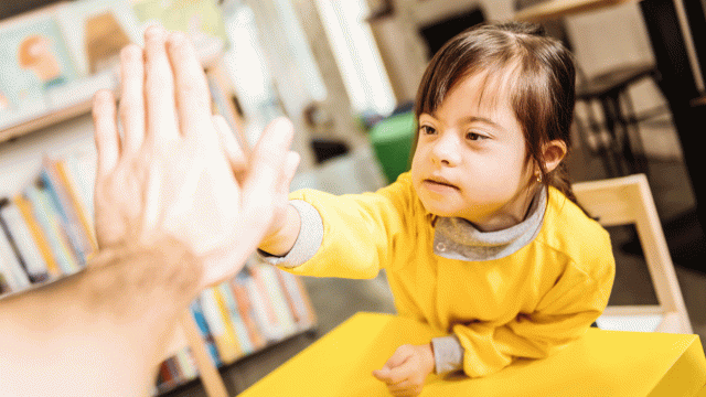 A disabled child gives her teacher a high five