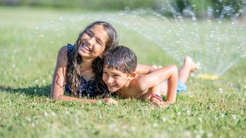 playing in the sprinkler is a fun summer bucket list idea