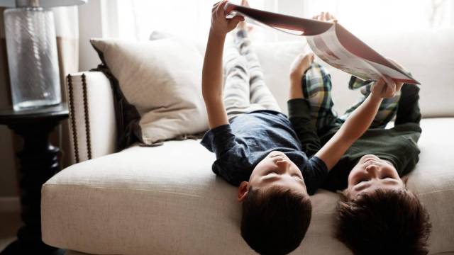 kids reading books on the couch upside down together