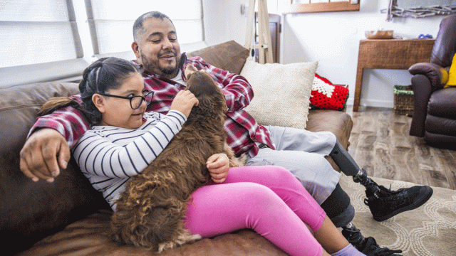 A Latinx family cuddles with their dog on the couch