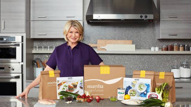 Martha Stweart stands in the kitchen next to her meal delivery services kit