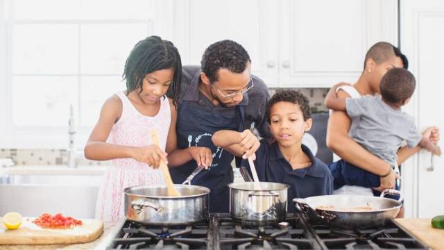 families cook together over two saucepans in the kitchen