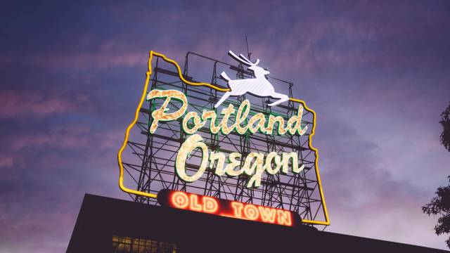 The Portland Oregon old town sign with a deer lit up at night