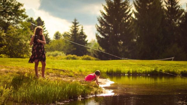 children fishing at scenic pond