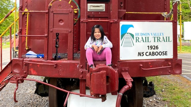 girl sitting on red caboose at walkway over the Hudson ny
