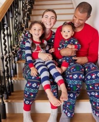 family of four sitting on staircase in matching holiday pajamas