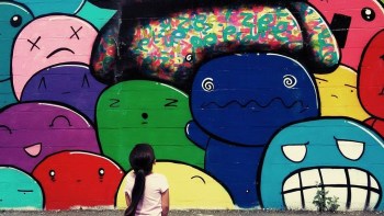 a young girl looks at colorful figures on a mural in Boston