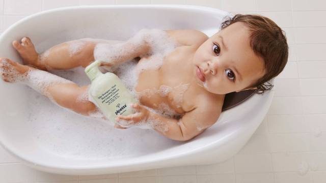 baby in bath with bubbles holding Pipette bottle