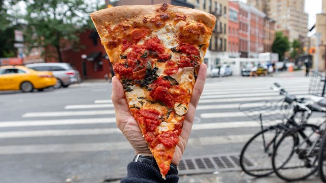 hand holding slice of pizza on NYC street