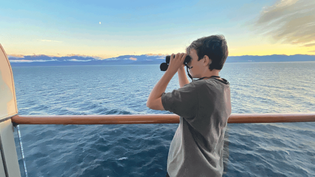 teen looking through binoculars on holland america alaska cruise