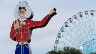 giant cowboy sign in front of Ferris wheel at State Fair of Texas