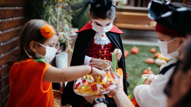 kids trick or treat in costume at a door on Halloween
