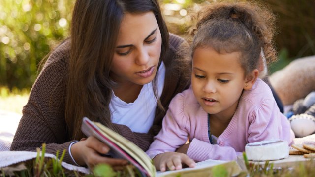 mom reading to daughter outside