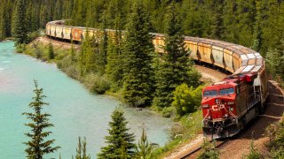 train moving through forest and lake