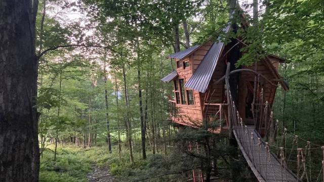 This whimsical treehouse with lopsided roof and a long suspension bridge is a top treehouse rentals new england