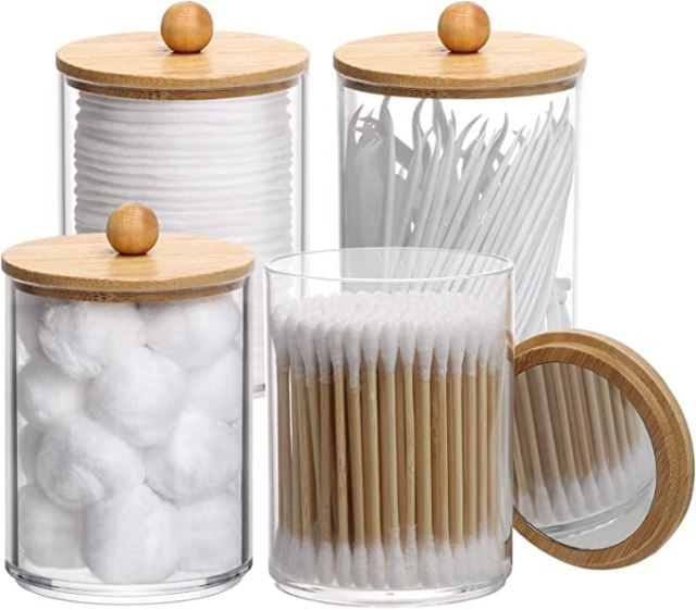 Four apothecary jars filled with q-tips, cotton pads, cotton balls, and floss picks
