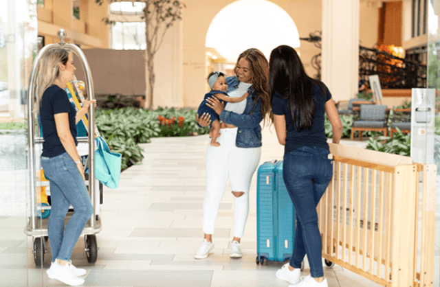 Mom and baby speaking to two woman by a luggage rack