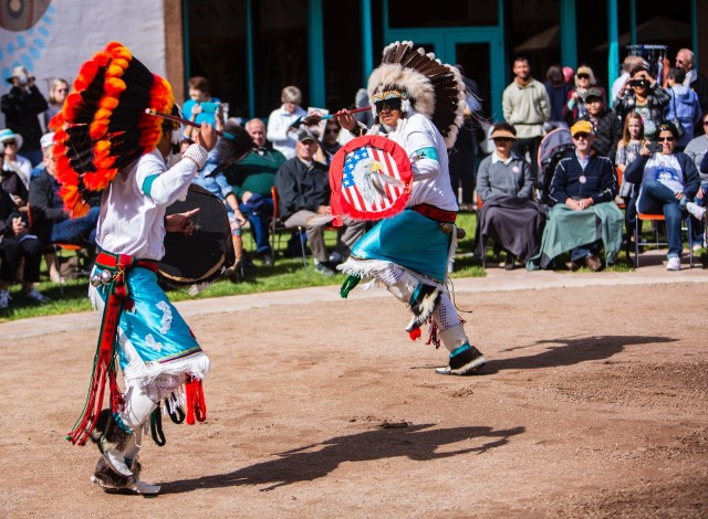 Native American performers in traditional attire dancing.
