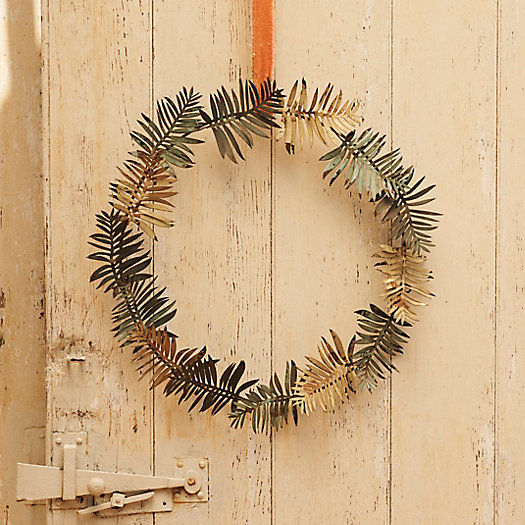 An iron wreath shaped as palm leaves hands on a wooden background