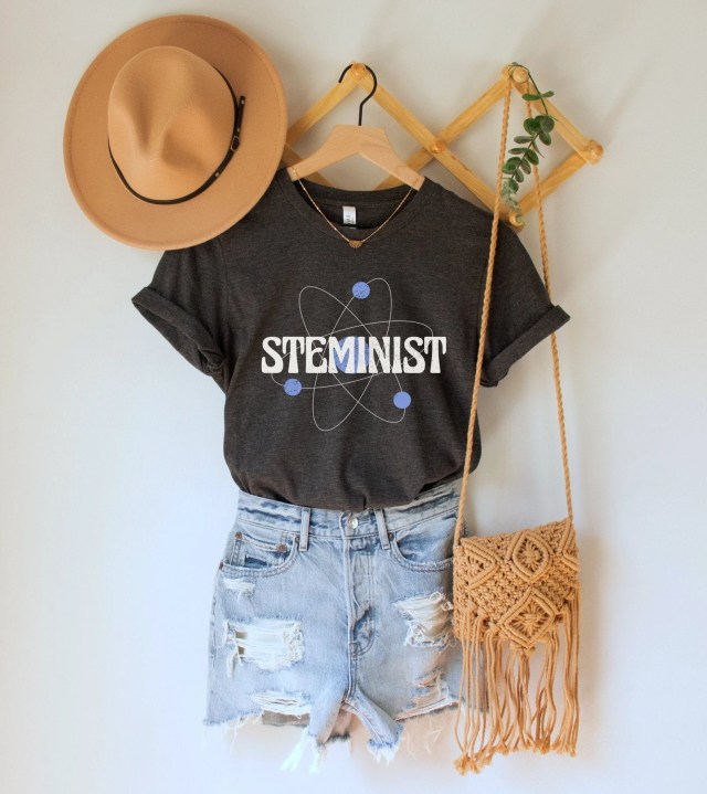 Steminist t-shirt, hat, and bag, hanging on wall peg