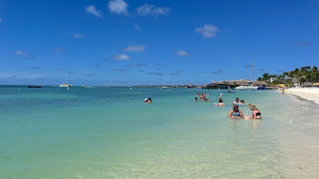 people swim in the warm waters on a beach in aruba one of the best things to do in aruba
