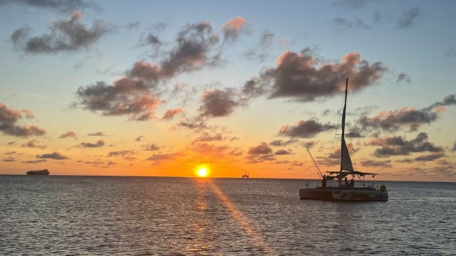 a boat at sunset on the water in Aruba with the sun setting in the background