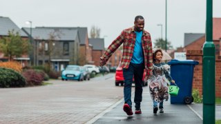dad and daughter trick-or-treating in neighborhood on Halloween