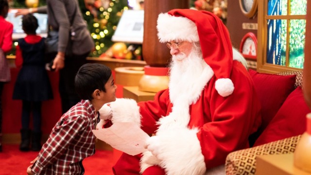 a boy stands in front of Santa during Santa pictures waiting to tell him what he wants for Christmas