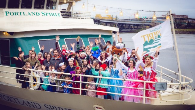 a group of people aboard the Portland Spirit wave on the front of the ship during the Cinnamon bear breakfast, a portland christmas event everyone loves