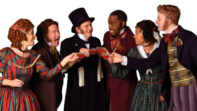 the cast of ACT Christmas carol in costumes from victorian england clinking glasses