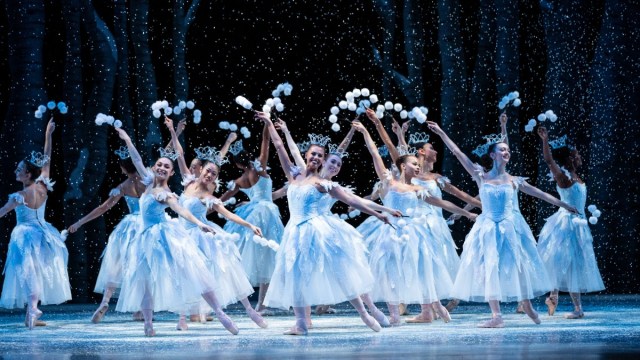 dancers in white ballet costumes dance among snow at PNB's Nutcracker Ballet during Christmas shows in Seattle